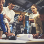 A group of people standing around a table, writing on charts