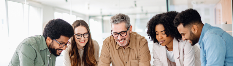 Five adults stand around a laptop on a table