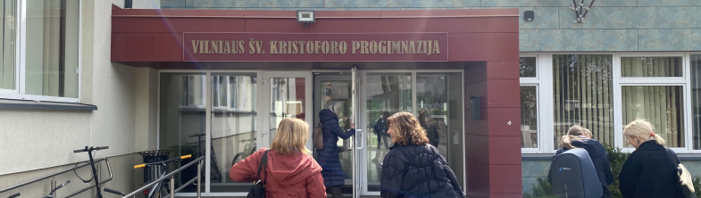 Four people walking up to the door of a school