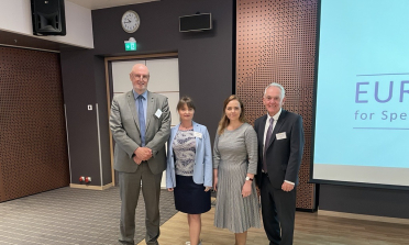 Four people standing in front of a presentation screen
