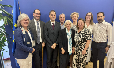 A group of nine people standing in front of a bright blue wall.