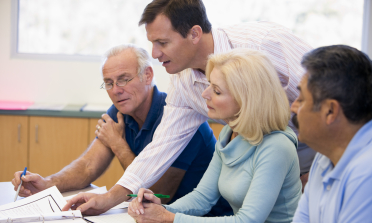 Four policy-makers sit at a desk and discuss a paper